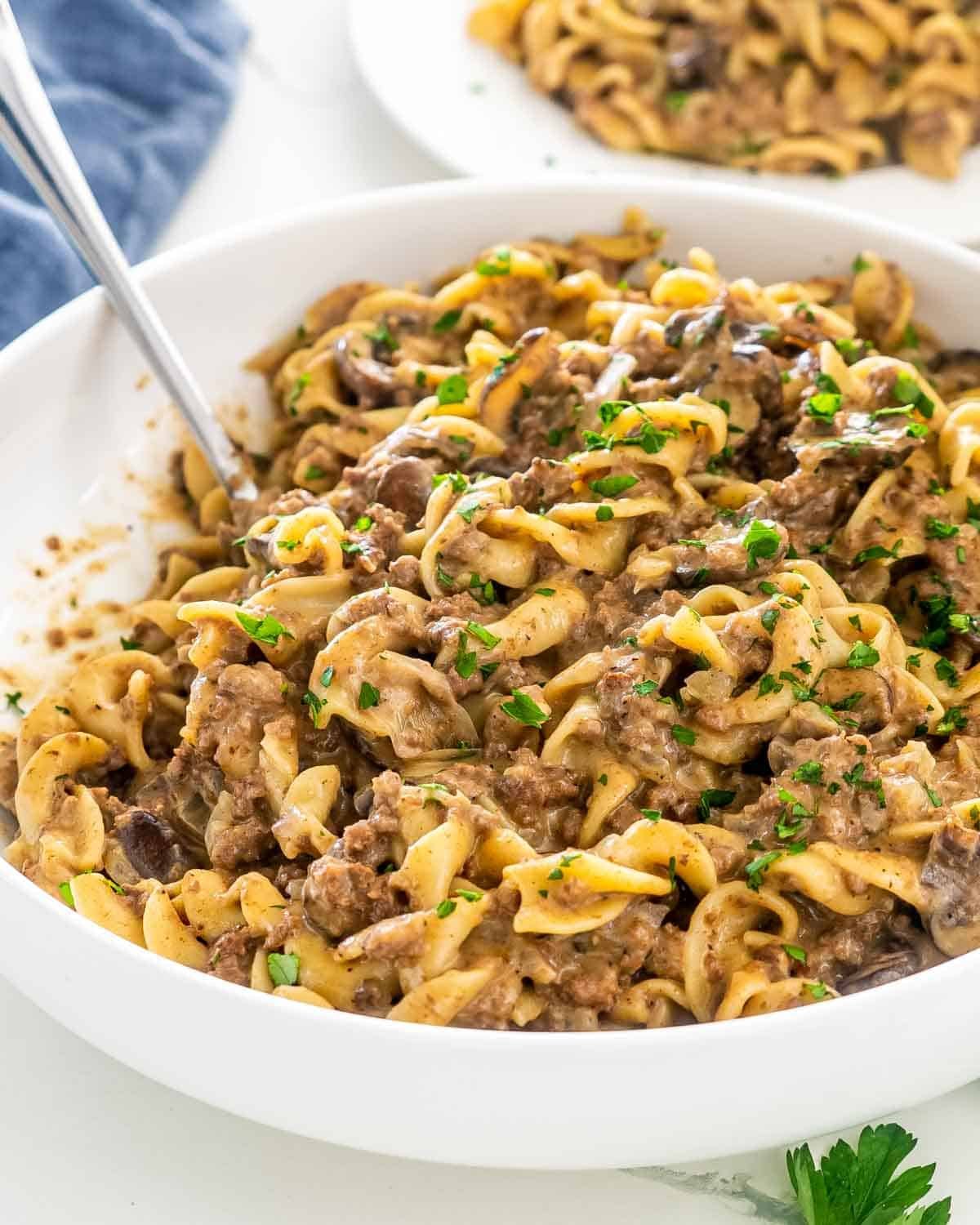 beef stroganoff in a white bowl with a serving spoon.