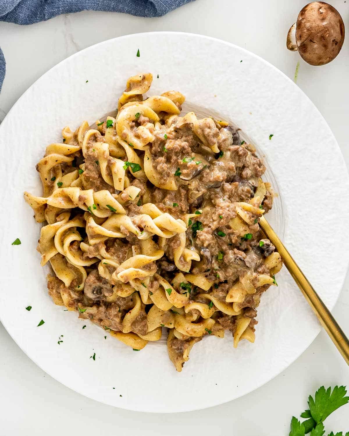 beef stroganoff on a white plate with a golden fork.