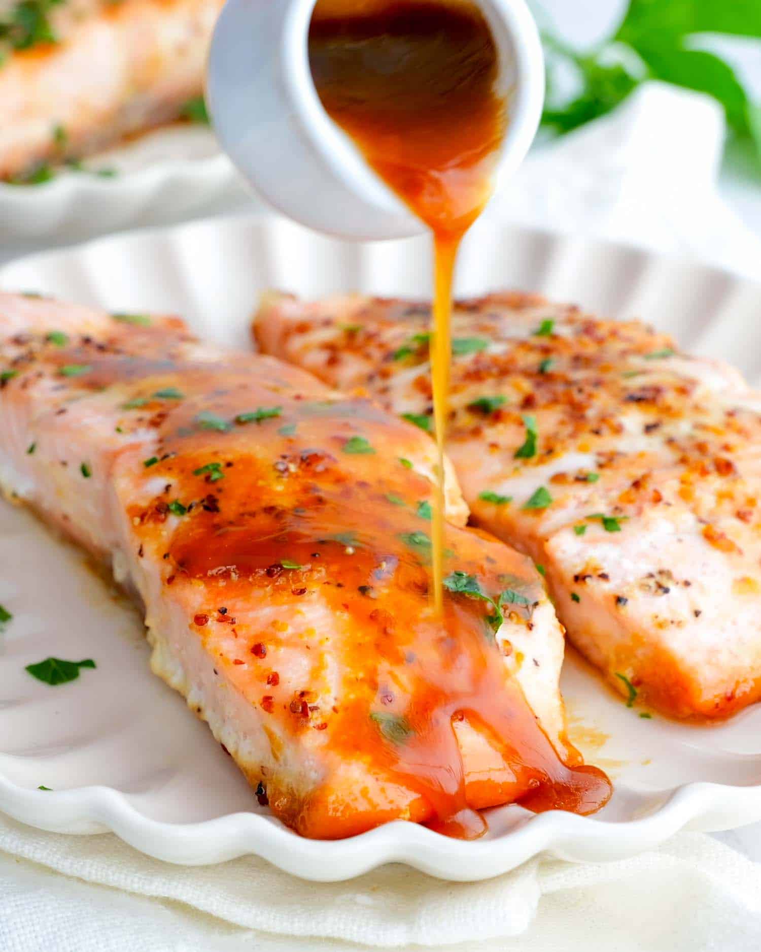 two pieces of maple mustard glazed salmon on a white plate.