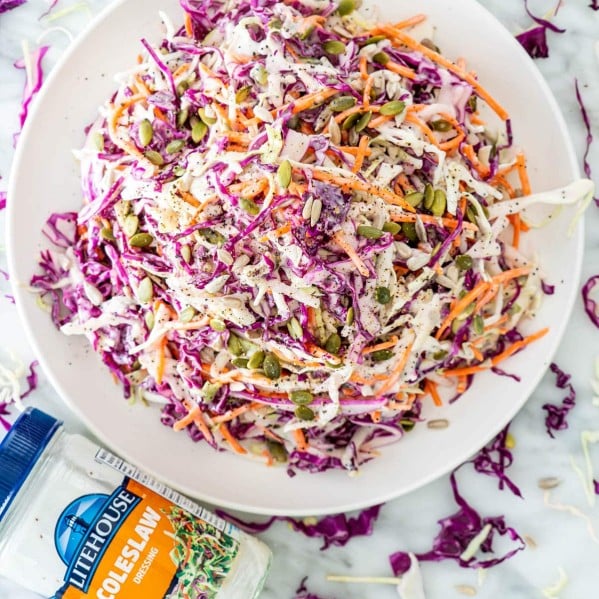 overhead shot of a bowl of mixed cabbage apple coleslaw with a jar of litehouse coleslaw dressing on the side