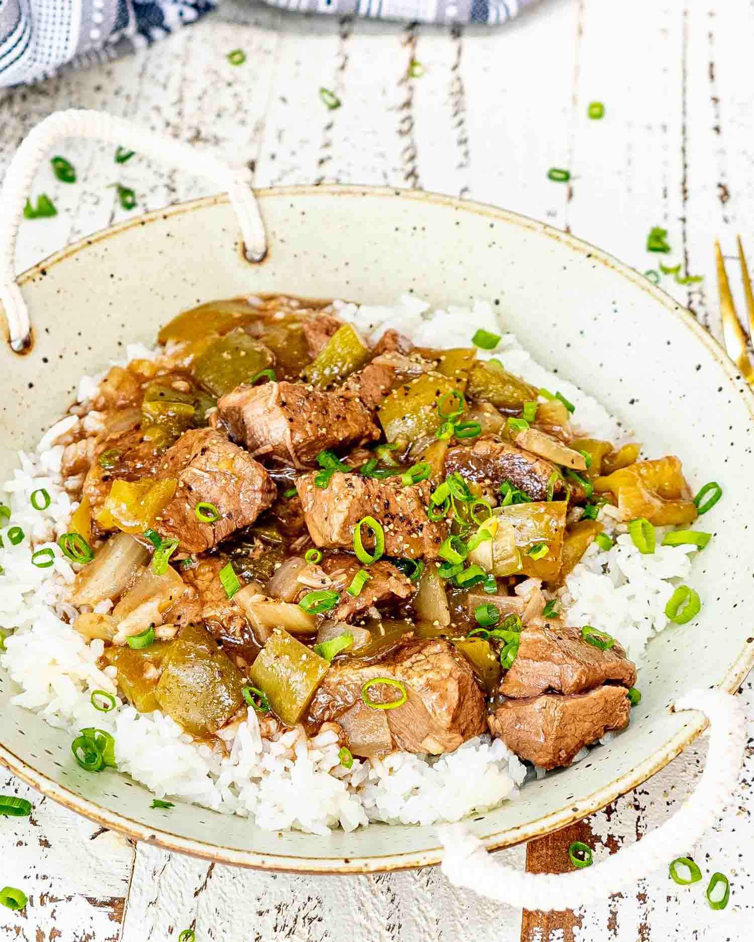 a serving of slow cooker pepper steak on a bed of white rice.