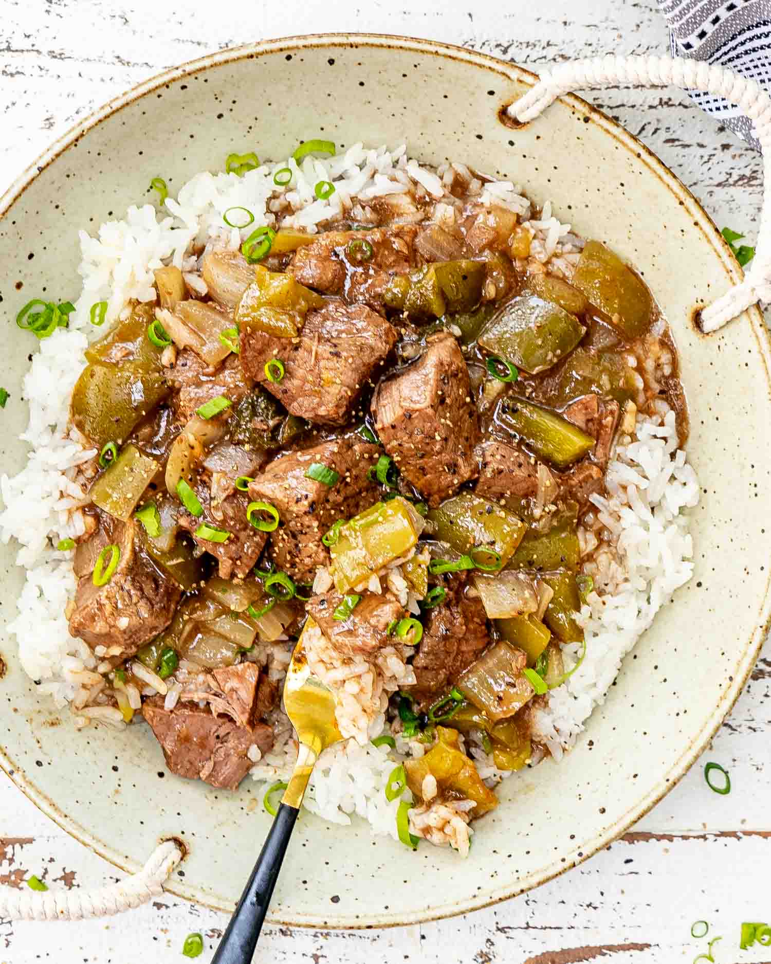 a serving of slow cooker pepper steak on a bed of white rice.
