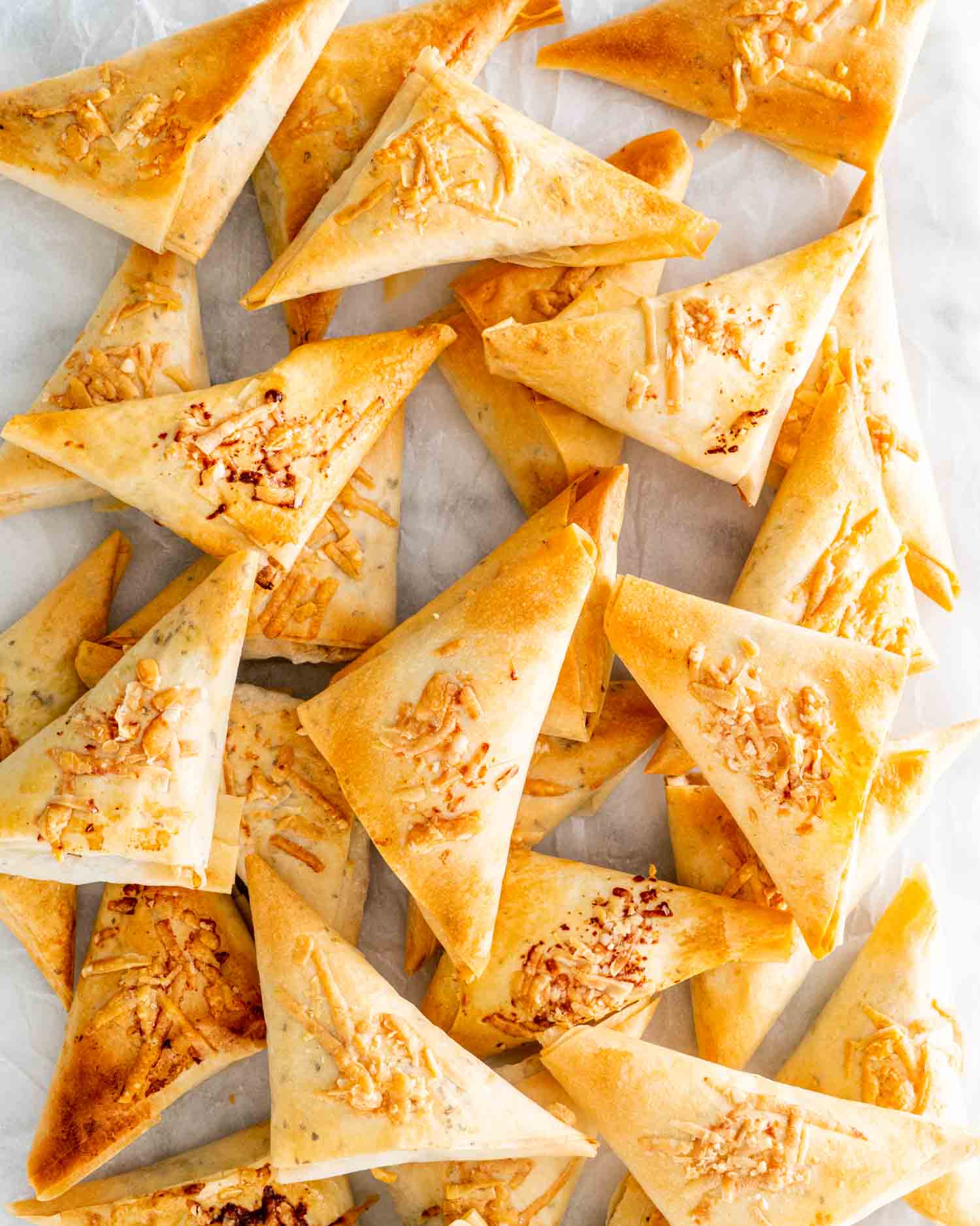 a bunch of spanakopita triangles on a white platter.