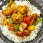 a serving of sweet and sour chicken over a bed of rice.