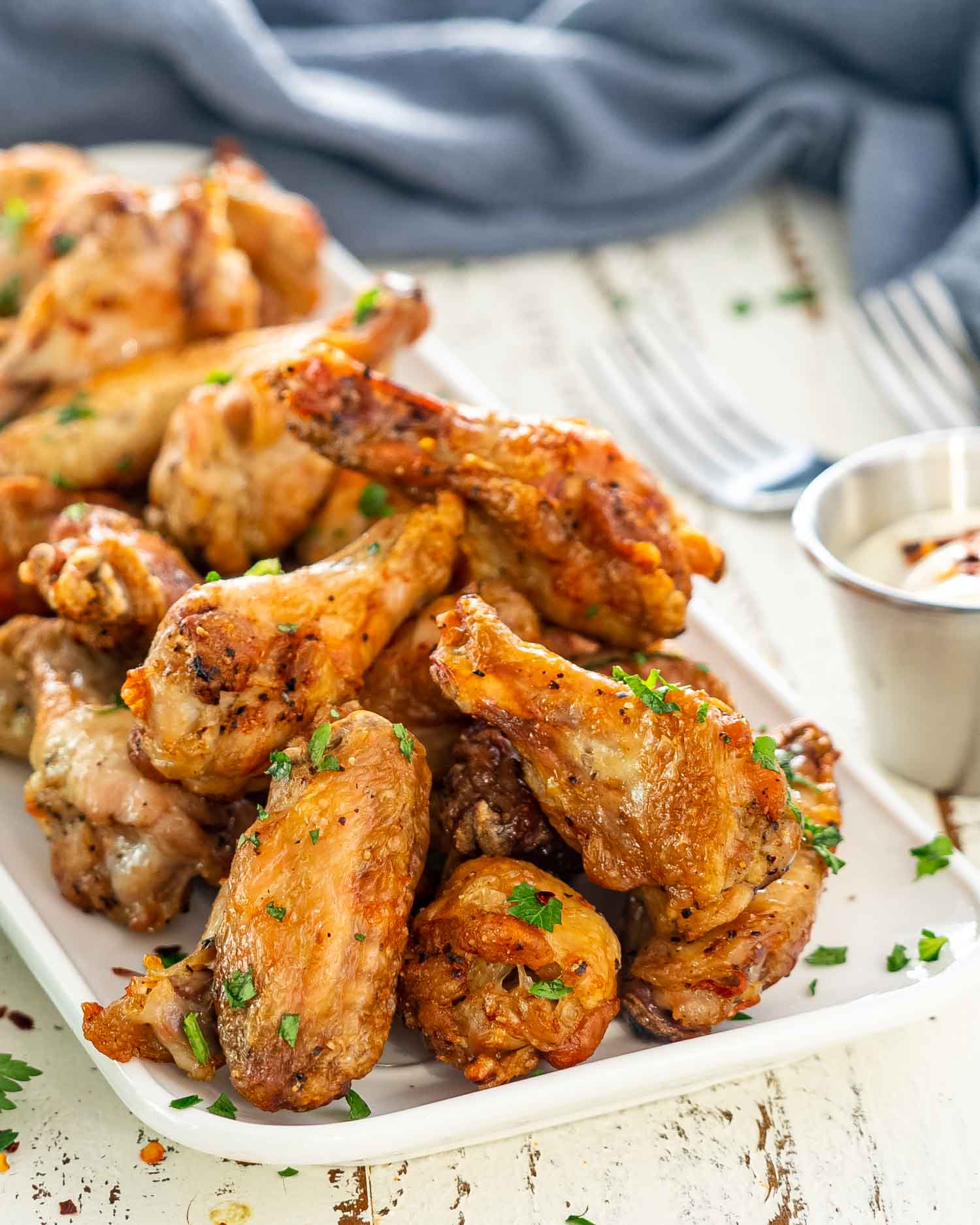 a few air fryer chicken wings on a white rectangular serving platter garnished with parsley.