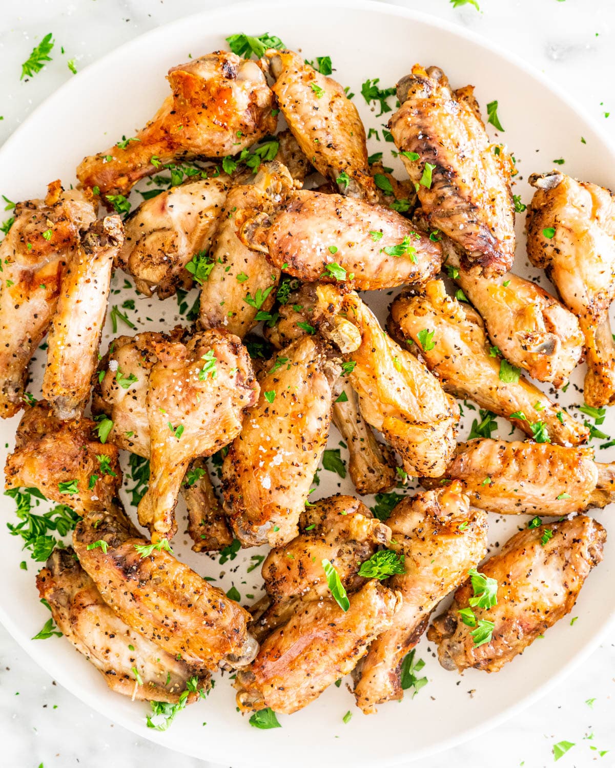 overhead shot of a white plate full of chicken wings garnished with parsley