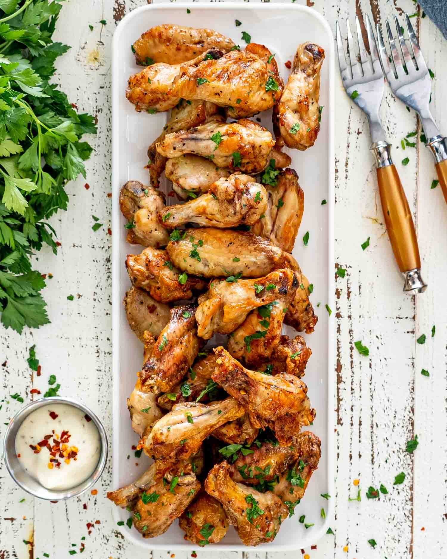 a few air fryer chicken wings on a white rectangular serving platter garnished with parsley.