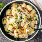 a serving of chicken florentine gnocchi in a black plate.