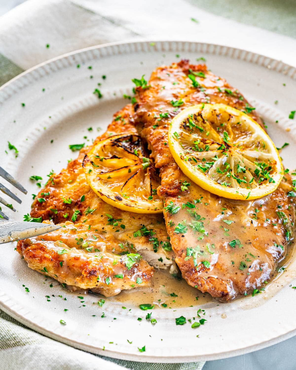 two pieces of chicken francese on a white plate