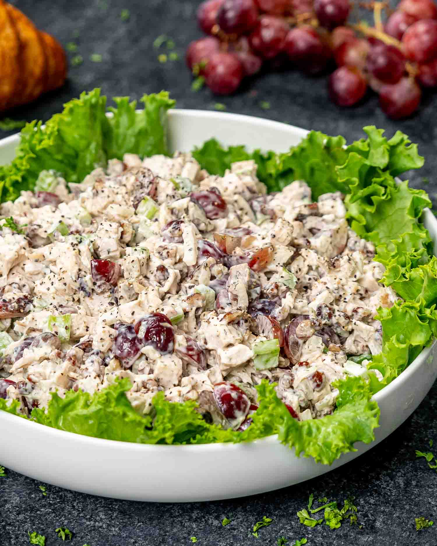 chicken salad in a white bowl lined with lettuce leaves.