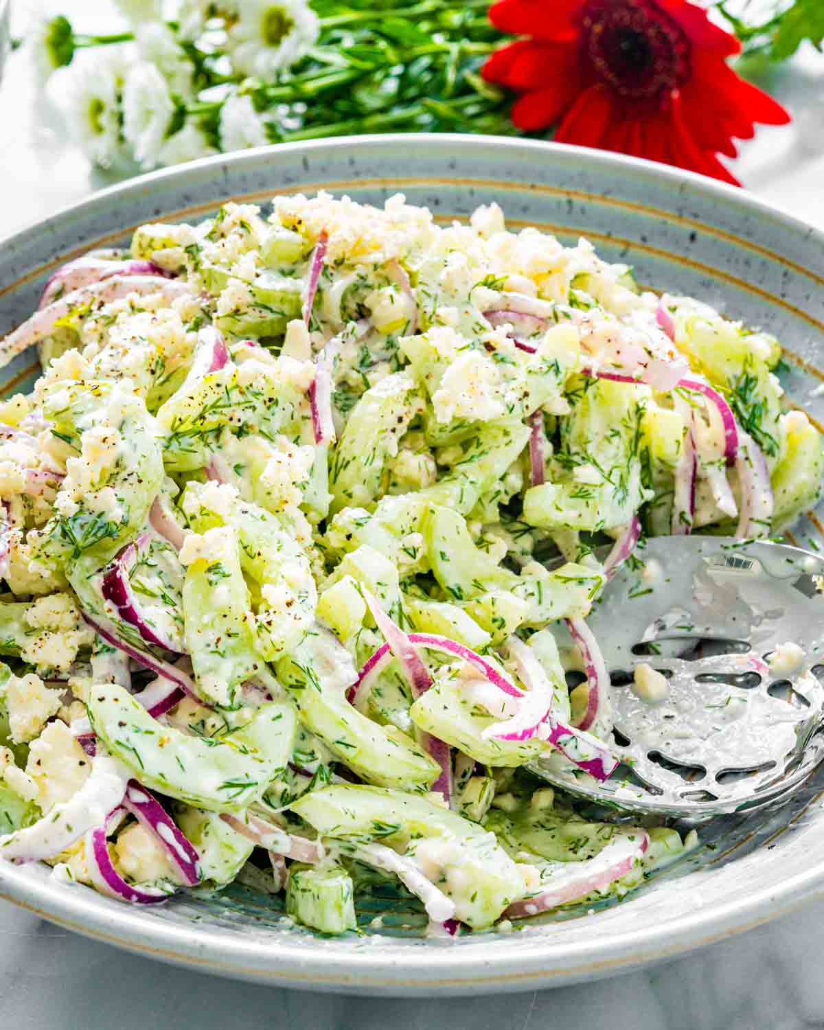 creamy cucumber salad in a big bowl with a serving spoon.