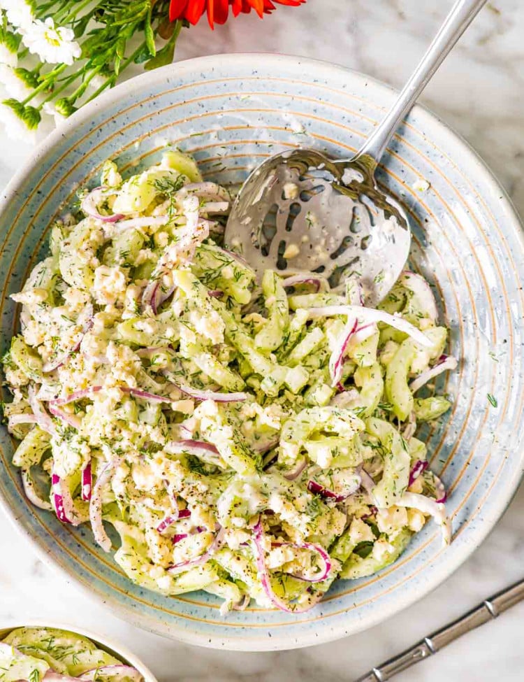 creamy cucumber salad in a bowl with a serving spoon.
