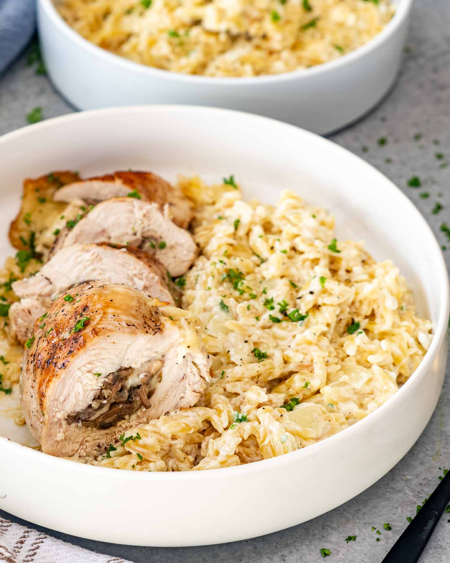 a serving of creamy garlic parmesan orzo with a mushrooms tuffed chicken breast.
