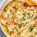 freshly made creamy sun dried tomato chicken gnocchi in a skillet garnished with parsley.