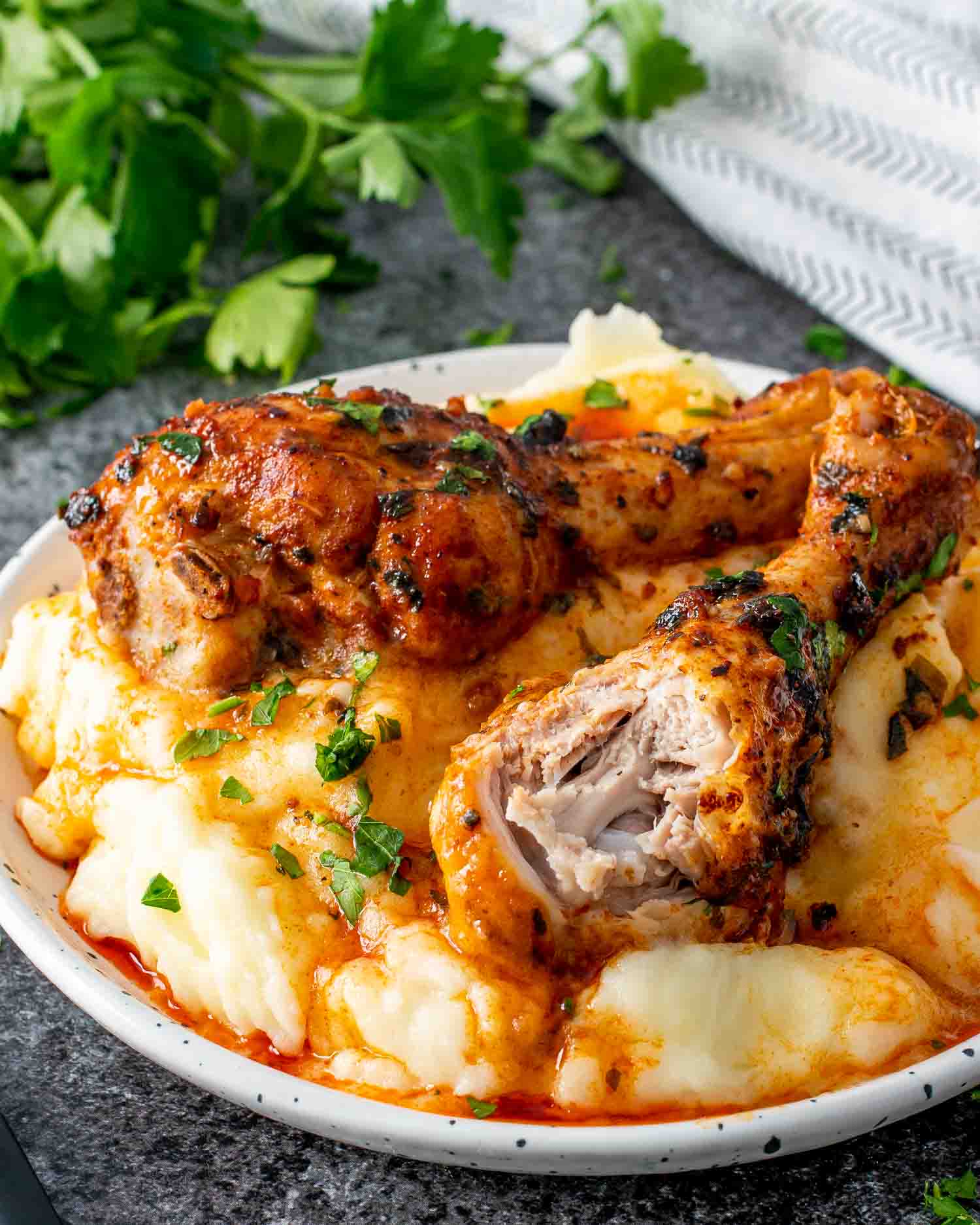 two garlic and paprika chicken drumsticks over a mashed potatoes garnished with parsley.