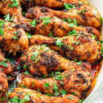 garlic and paprika chicken drumsticks garnished with parsley in a roasting pan.