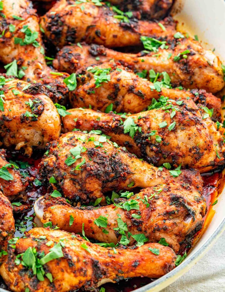 garlic and paprika chicken drumsticks garnished with parsley in a roasting pan.