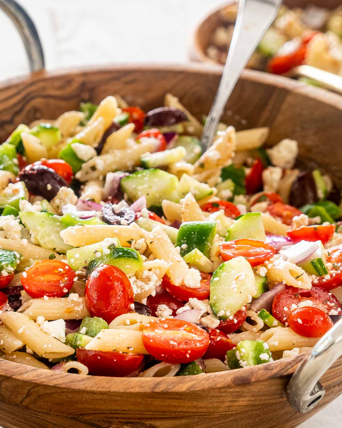 freshly made greek pasta salad in a wooden bowl.