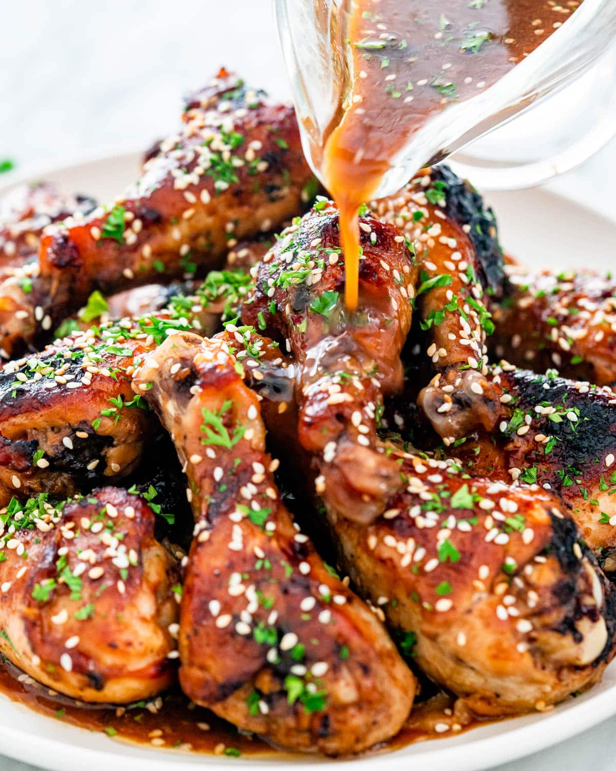 pouring sauce over Korean BBQ Chicken