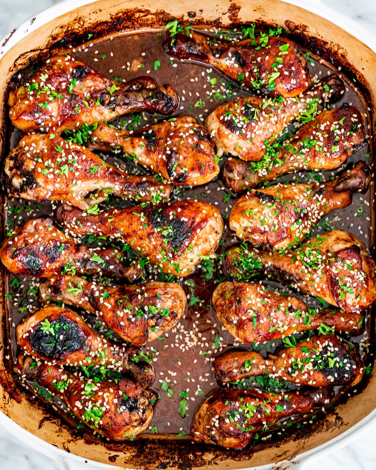 overhead shot of Korean BBQ Chicken in a baking dish garnished with parsley and sesame seeds