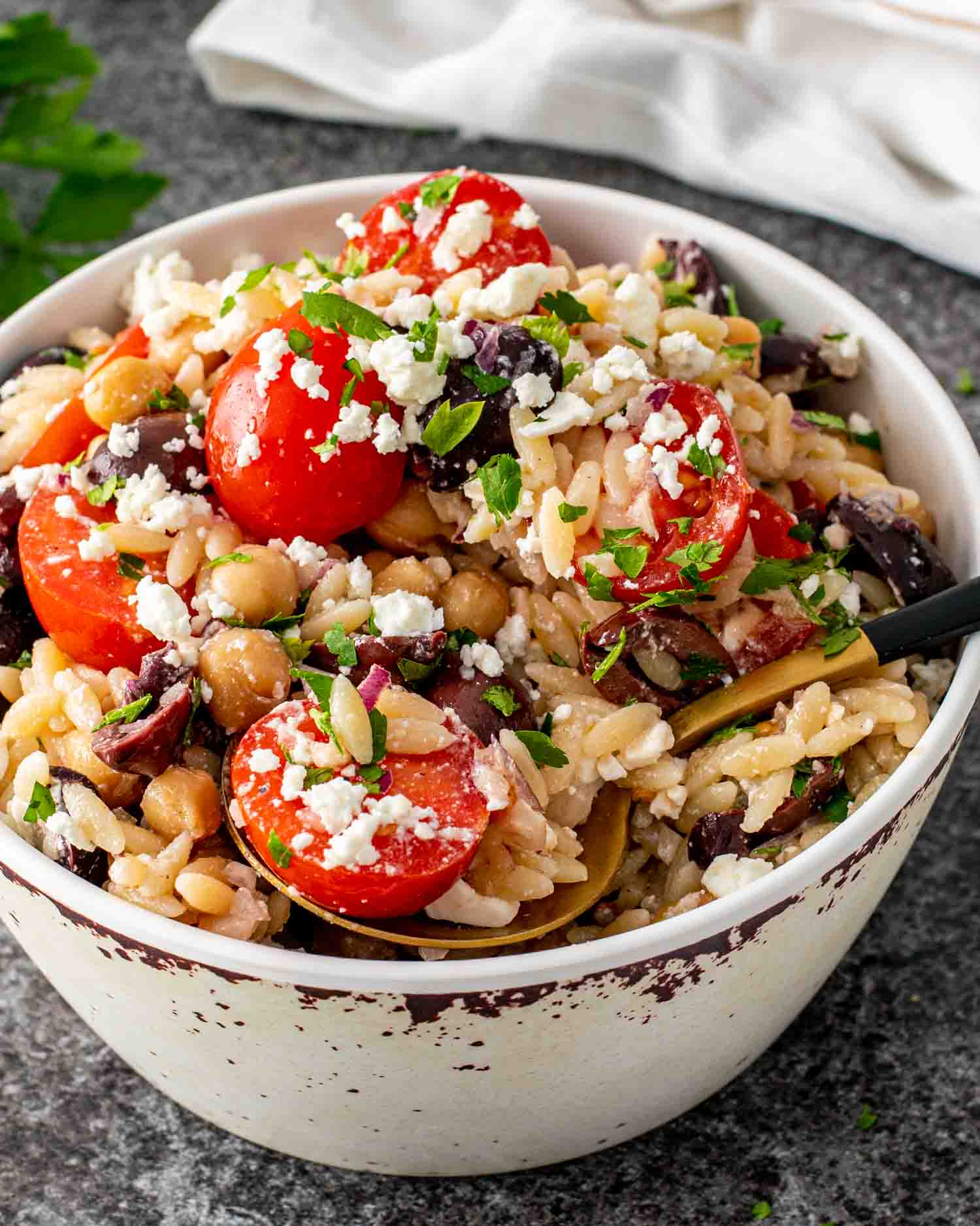 mediterranean orzo salad in a bowl garnished with feta cheese and parsley.