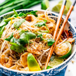 pad thai in a white and blue bowl with chopsticks on the plate.