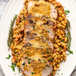 sliced rosemary garlic pork roast with gravy over white beans.