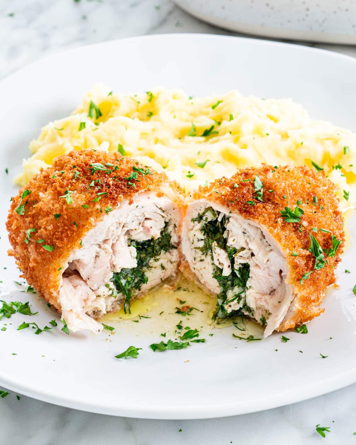 chicken kiev cut in half on a plate with mashed potatoes