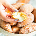 a hand holding a cinnamon cream cheese pocket that has a bite taken out of it