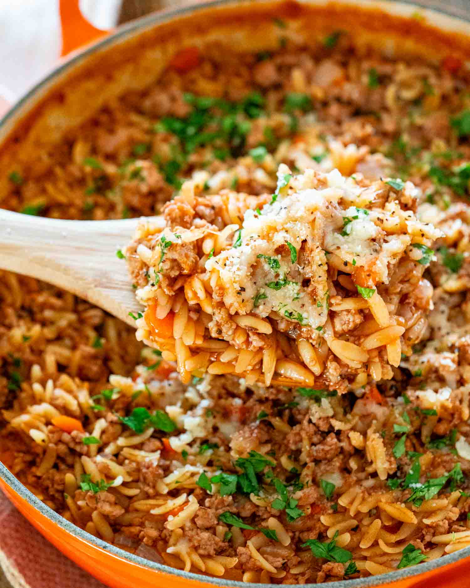 spicy pork ragu orzo garnished with parmesan and parsley in a skillet.