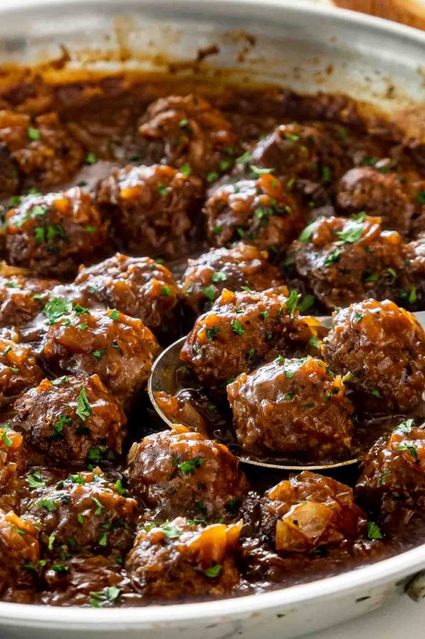 salisbury steak meatballs with gravy in a skillet garnished with parsley.