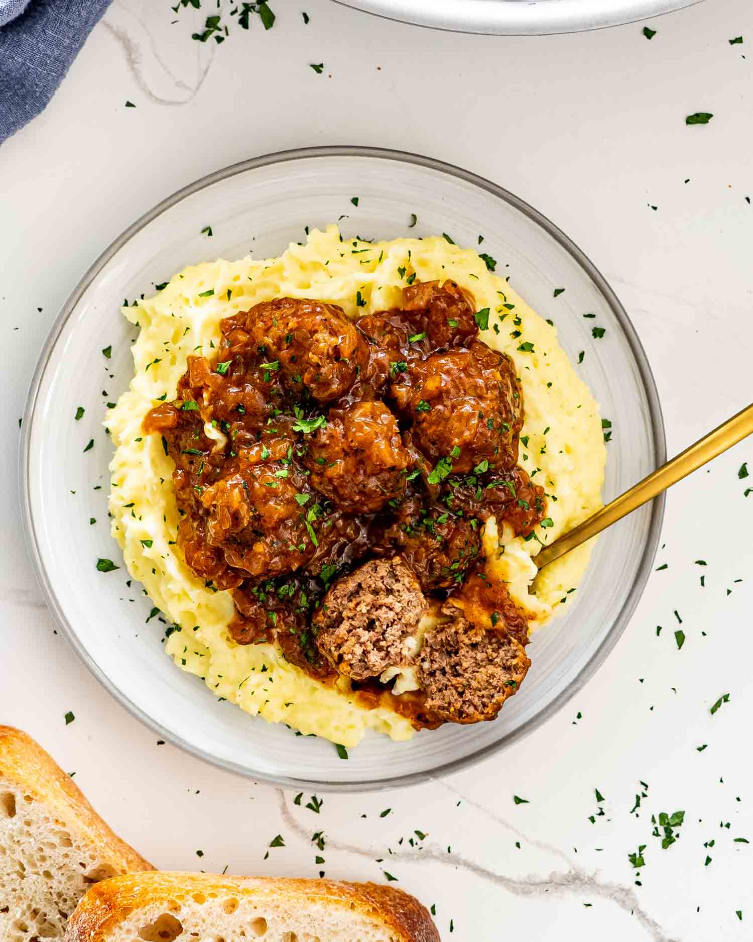 salisbury steak meatballs over a bed of mashed potatoes garnished with parsley.