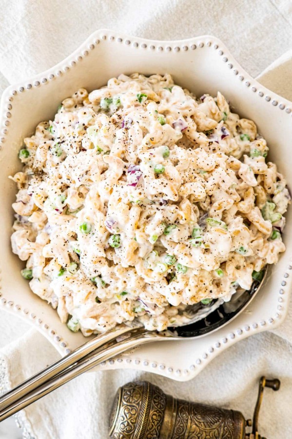 overhead shot of tuna macaroni salad in a decorative serving bowl with a serving spoon in it