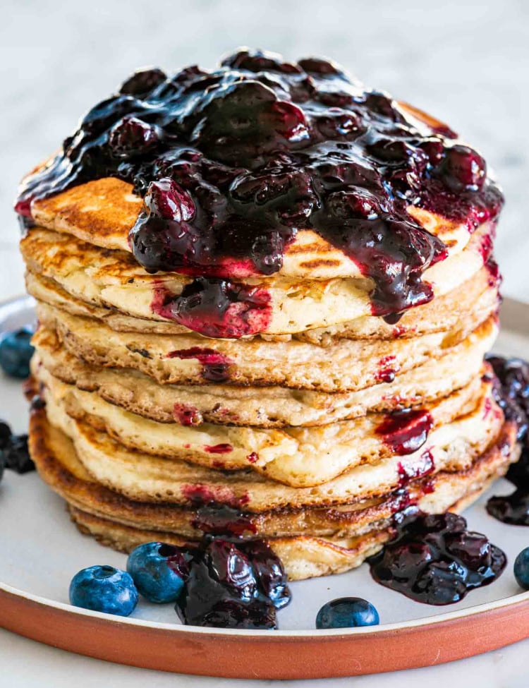 blueberry buttermilk pancakes on a plate with blueberry sauce on them.