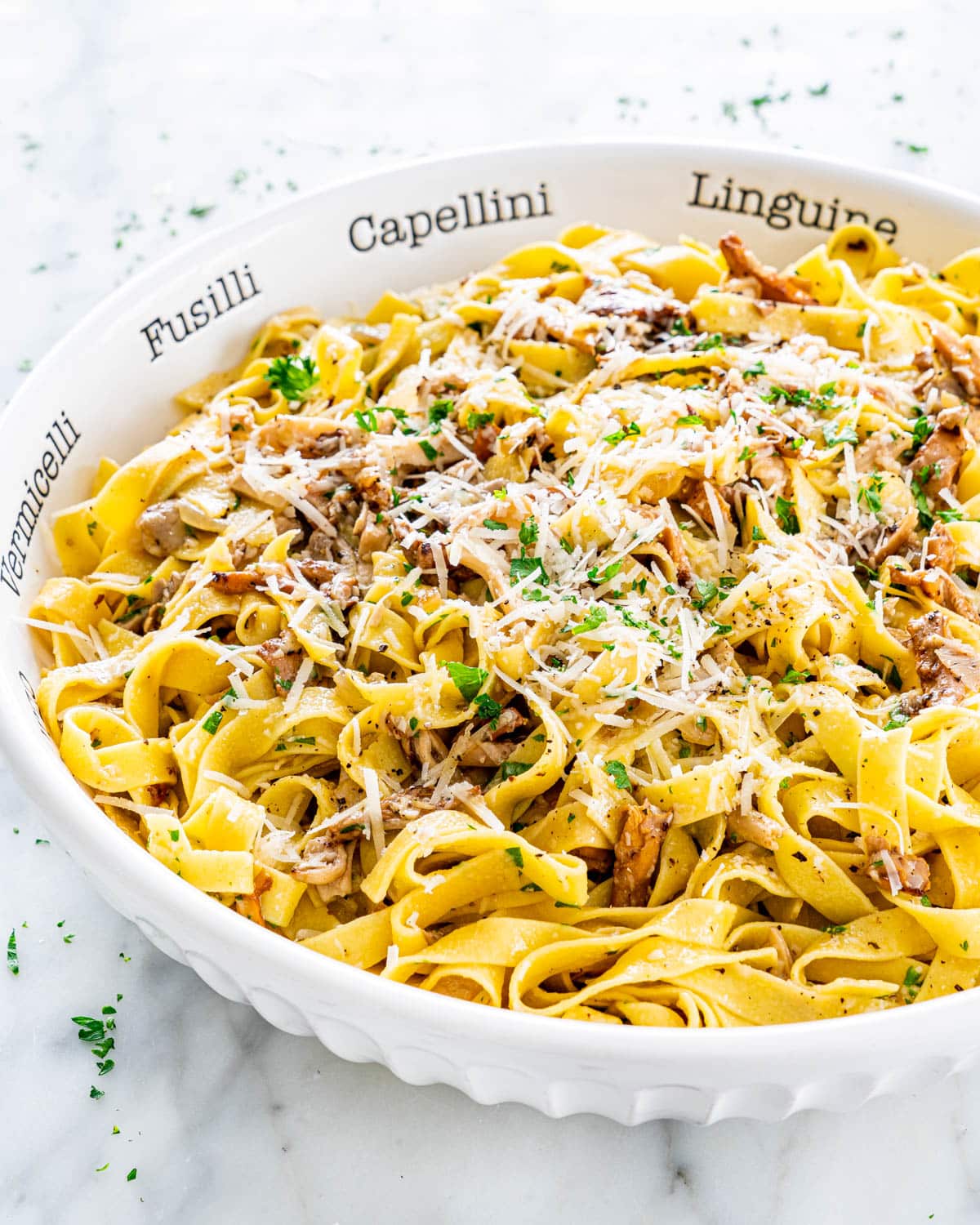 Chanterelle Mushrooms with Tagliatelle in a pasta bowl topped with parmesan cheese and parsley