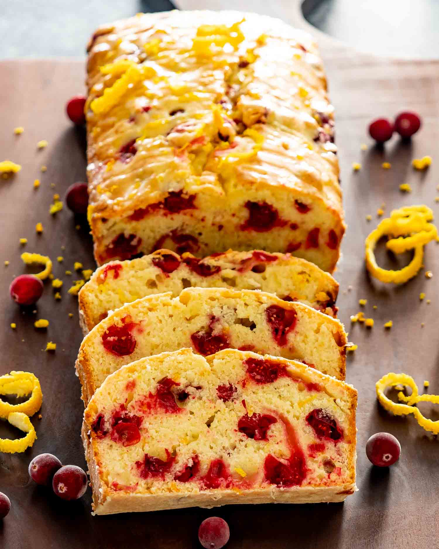 a cranberry orange bread with a few slices cut out of it on a cutting board.