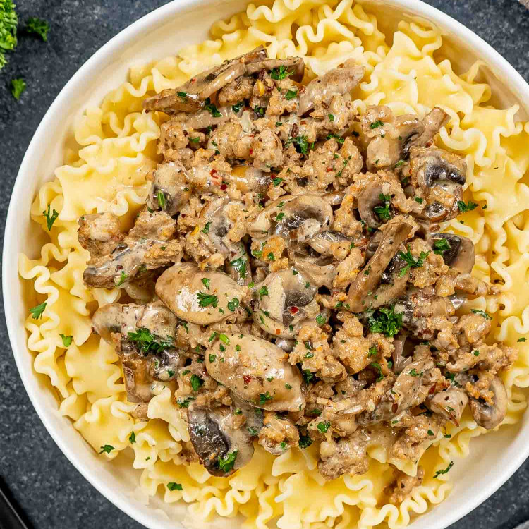 a serving of creamy sausage mushroom pasta in a white bowl.