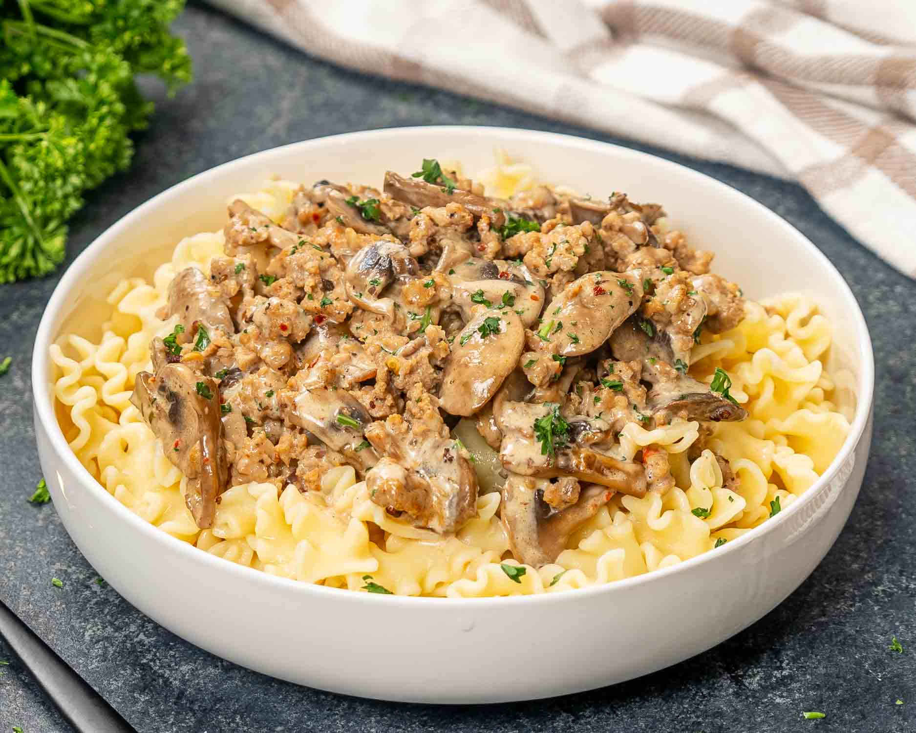a serving of creamy sausage mushroom pasta in a white bowl.