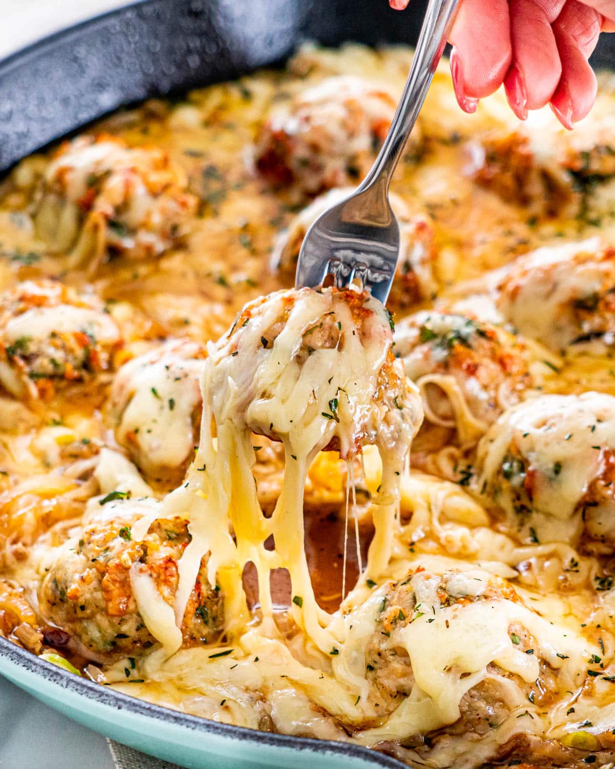 a fork picking up a meatball from a skillet