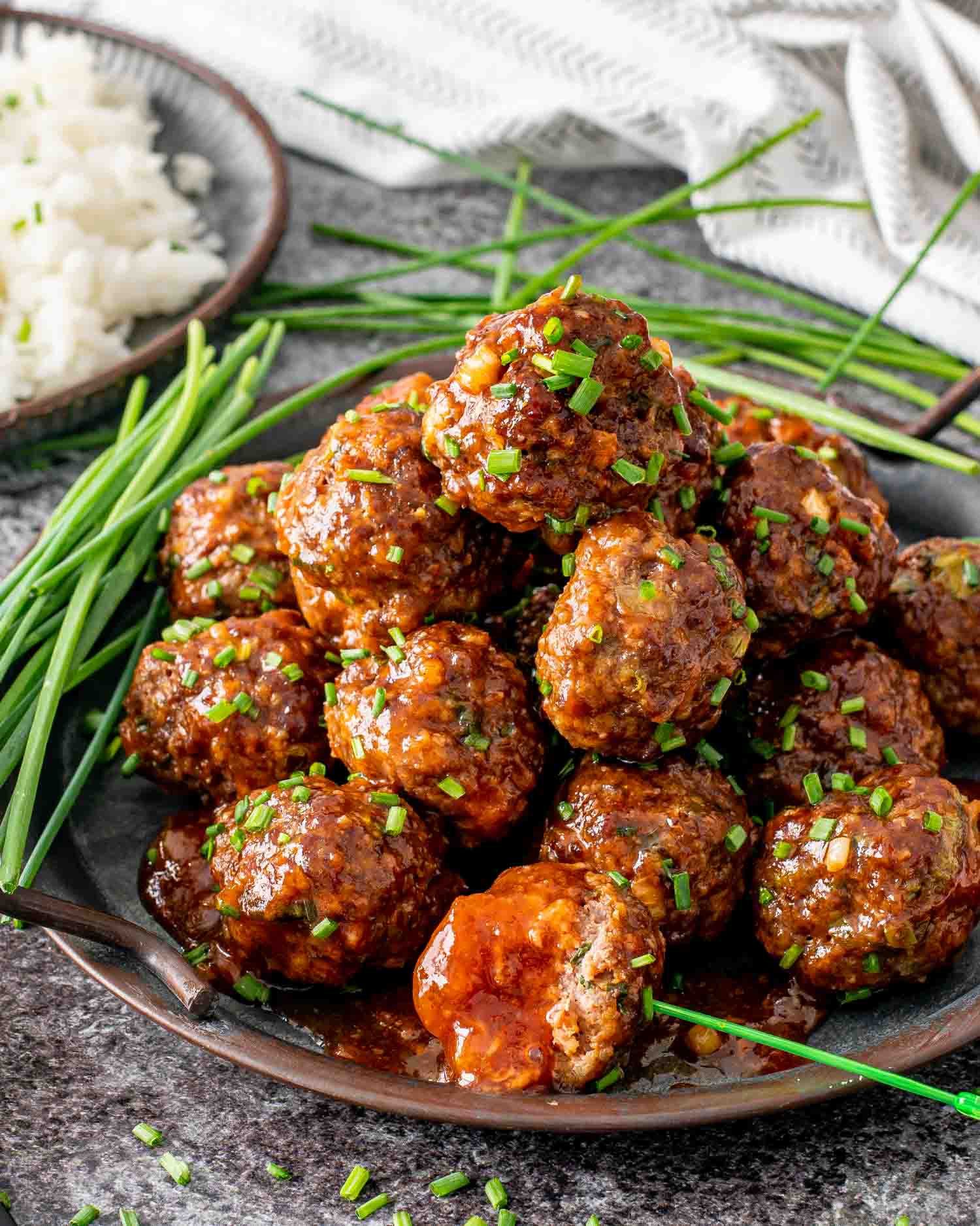 korean meatballs on a metal plate garnished with chives.