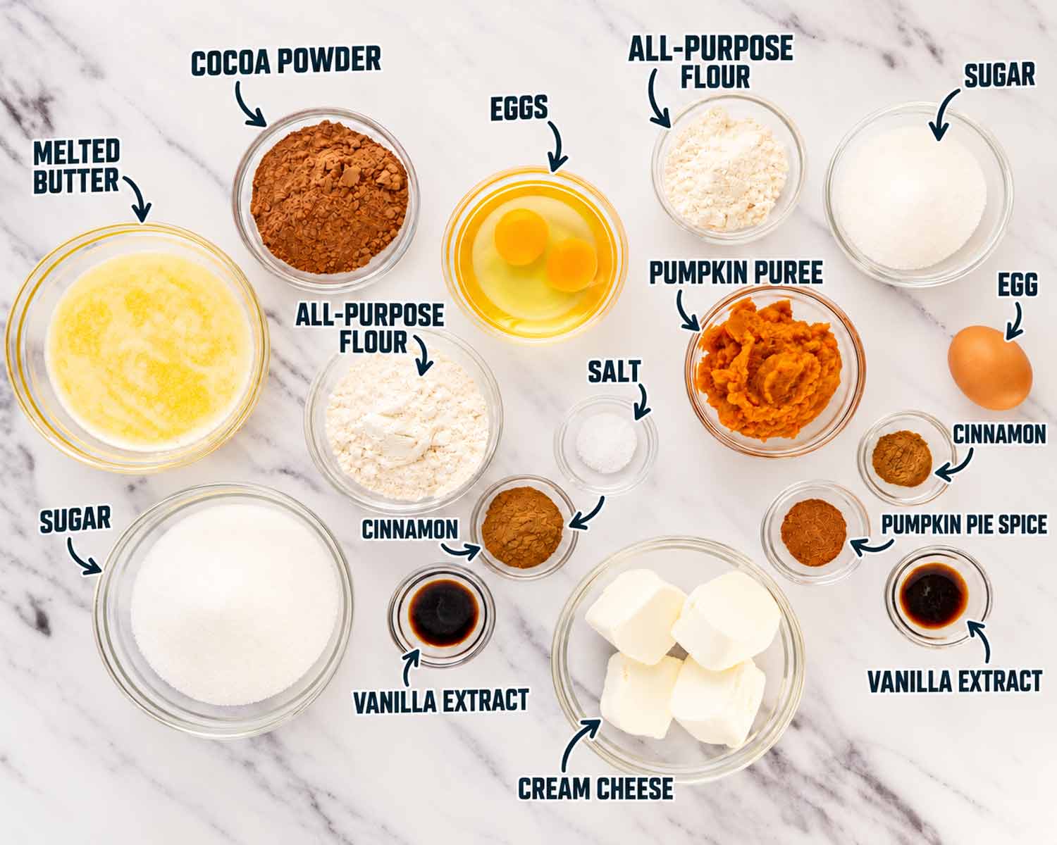 Labeled bowls of butter, cocoa, eggs, flour, sugar, pumpkin, salt, cinnamon, vanilla, pumpkin pie spice, and cream cheese for brownies.