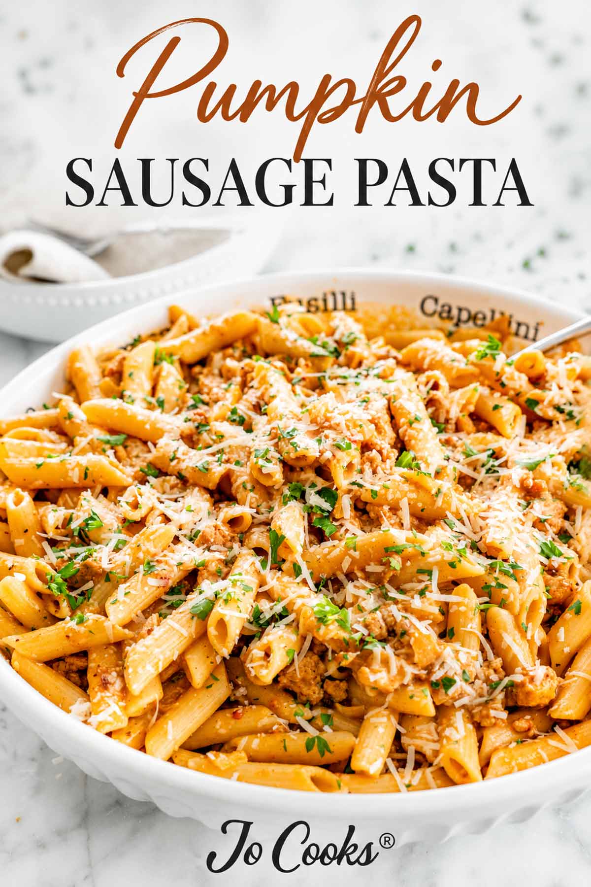 Creamy pumpkin sausage pasta topped with Parmesan and parsley, beneath an elegant recipe title, with the Jo Cooks logo below.