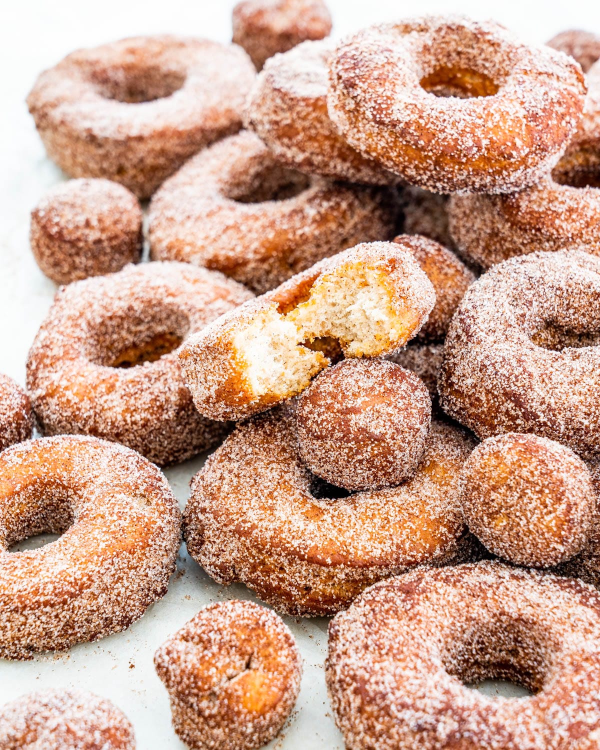 a bunch of apple cider donuts and donut holes on parchment paper