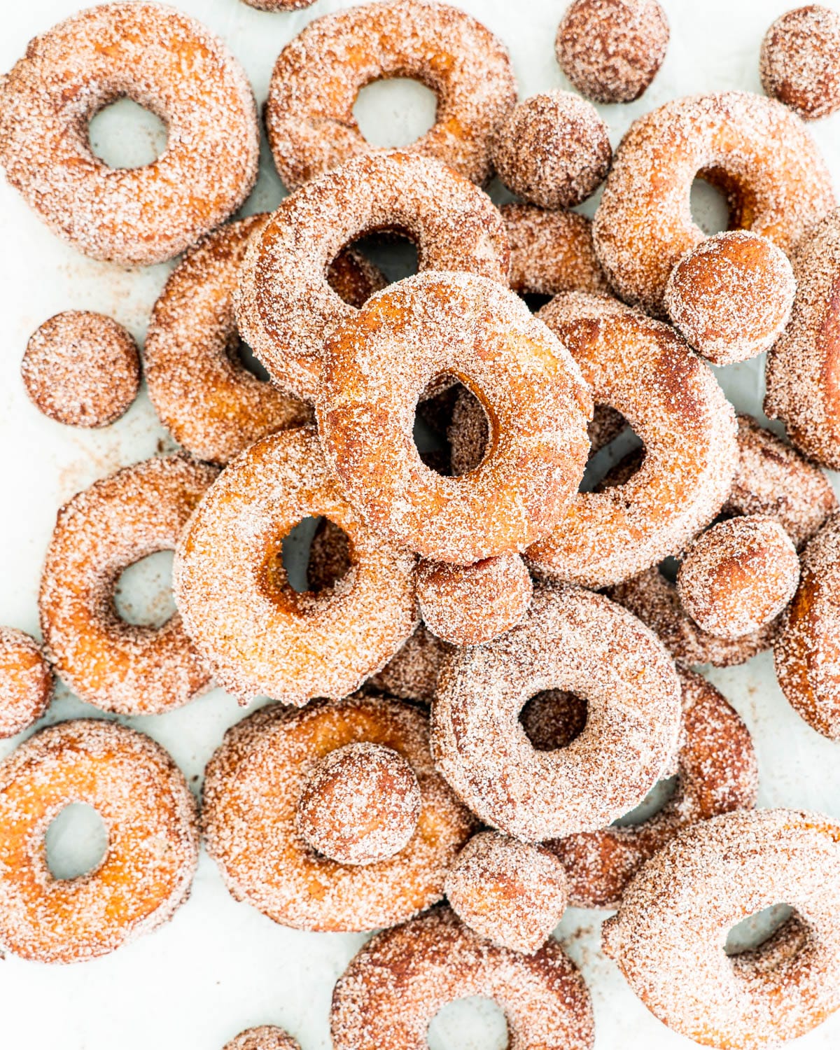 overhead shot of a bunch of apple cider donuts on parchment paper
