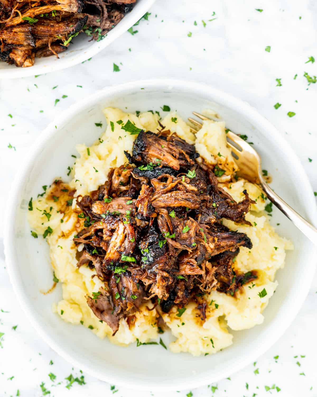pulled pork over mashed potatoes in a white bowl