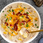 a serving of creamy potato soup in a white bowl with a spoon in it.