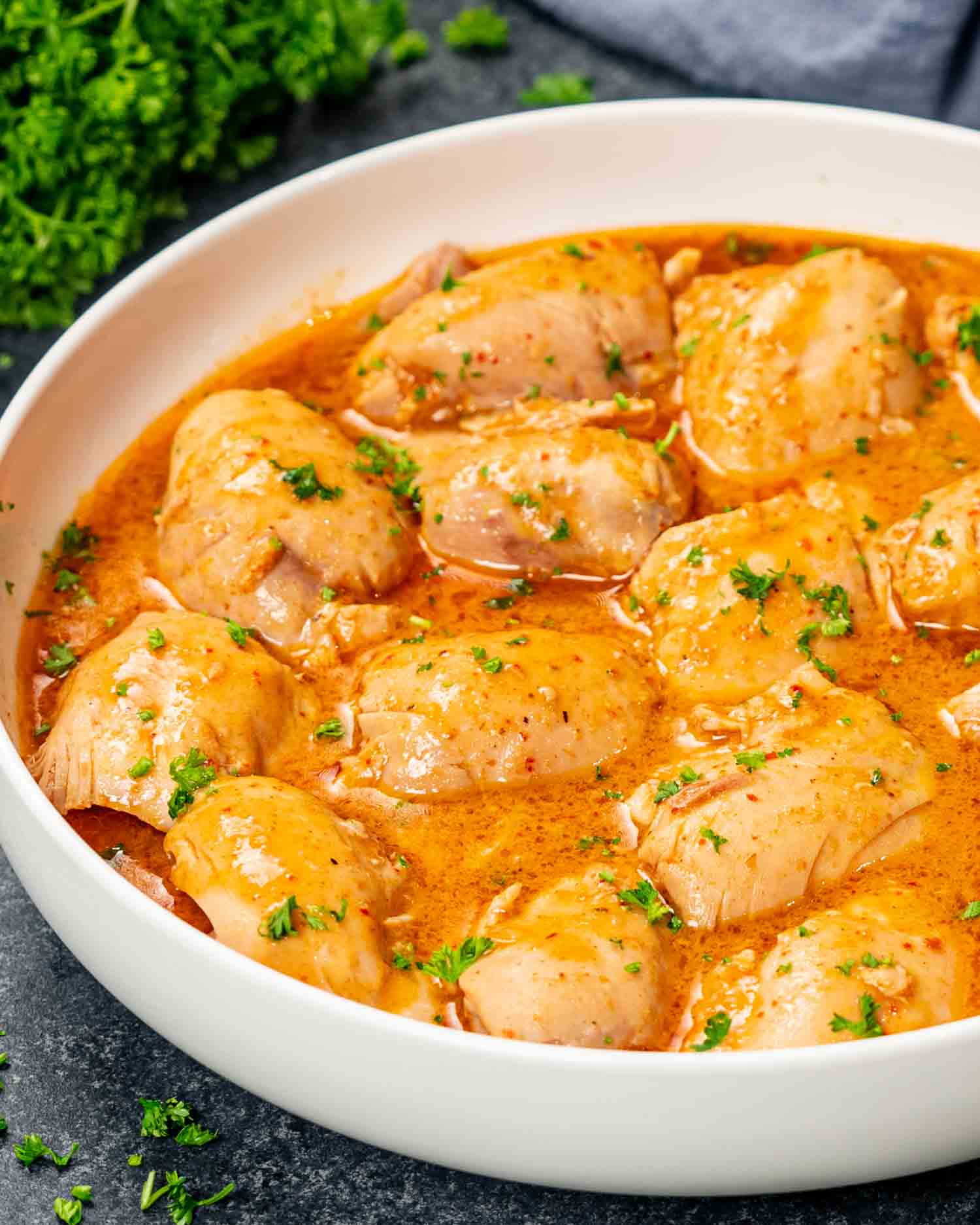 crockpot thai chicken thighs with sauce in a white bowl.