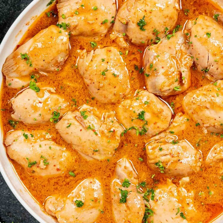 crockpot thai chicken thighs with sauce in a white bowl.