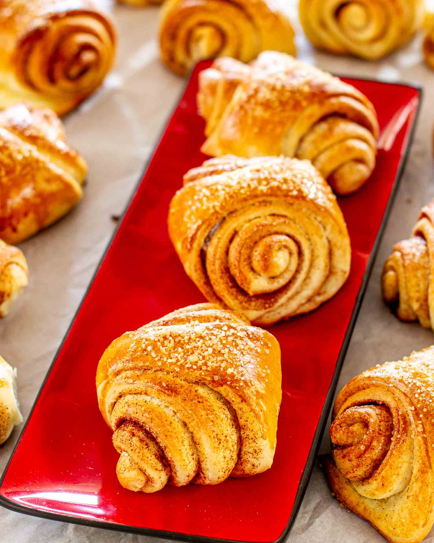freshly baked finnish cardamom rolls on a red plate.