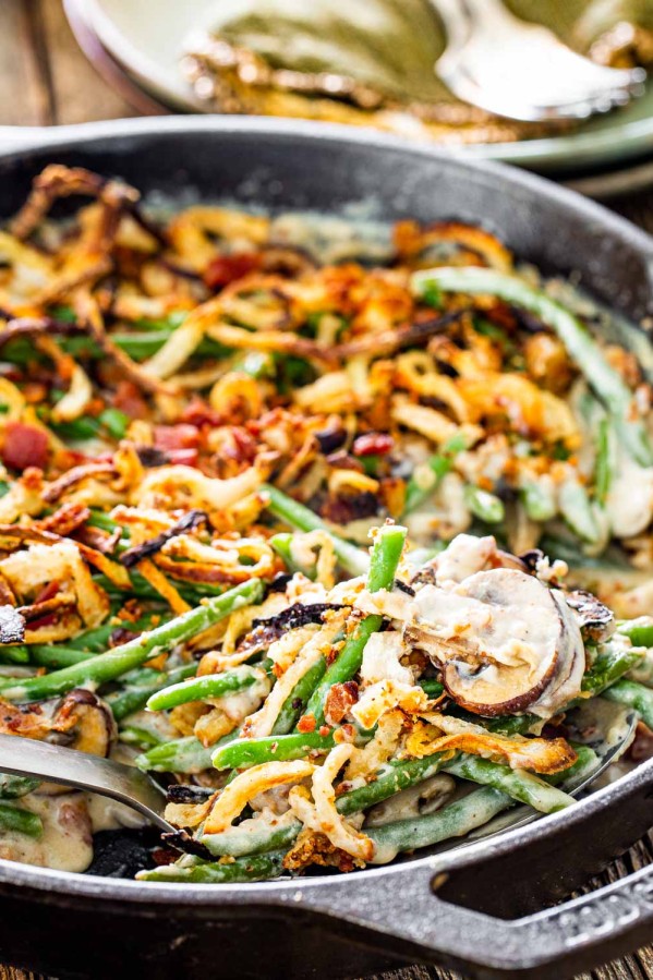 green bean casserole in a skillet with a serving spoon.